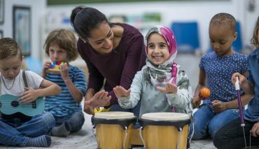 child plays drums with teacher and other children