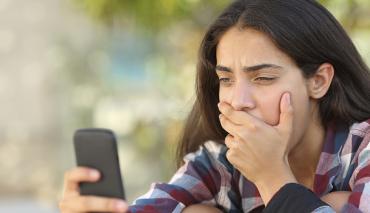 teenage girl recoiling at something on her mobile phone